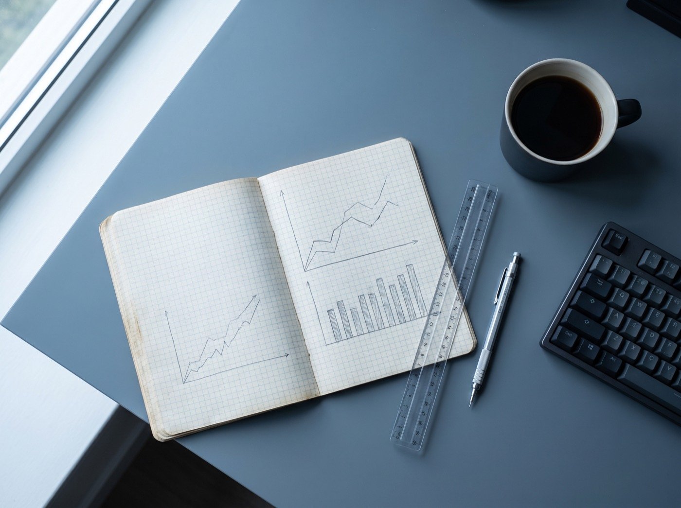 Hand-drawn charts in a notebook on a desk beside a ruler