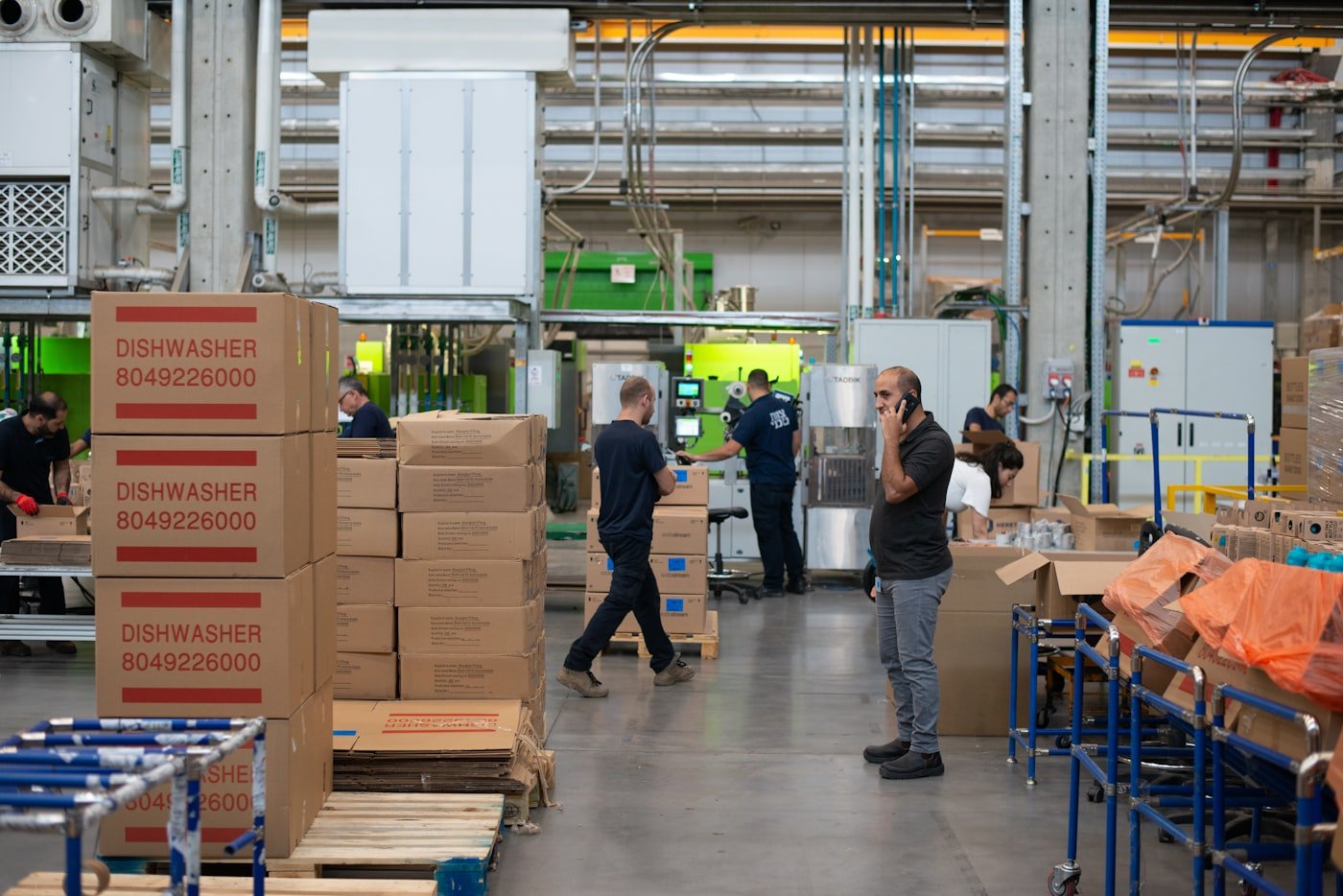 A warehouse worker beside stacked cardboard shipping boxes