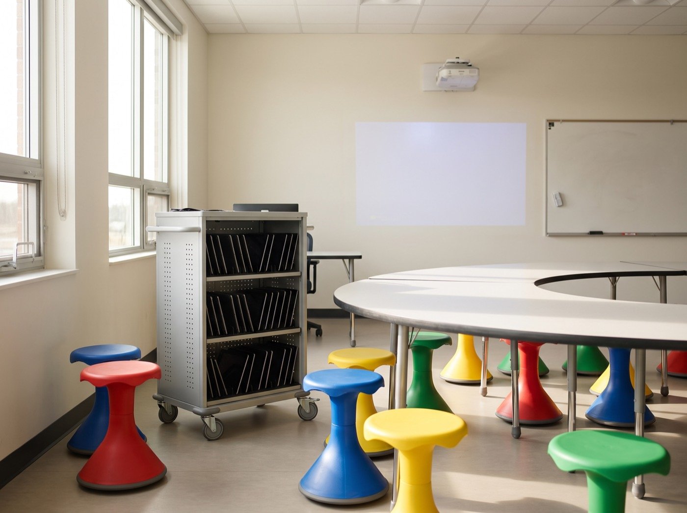 Tablet charging cart and coloured stools in a bright classroom