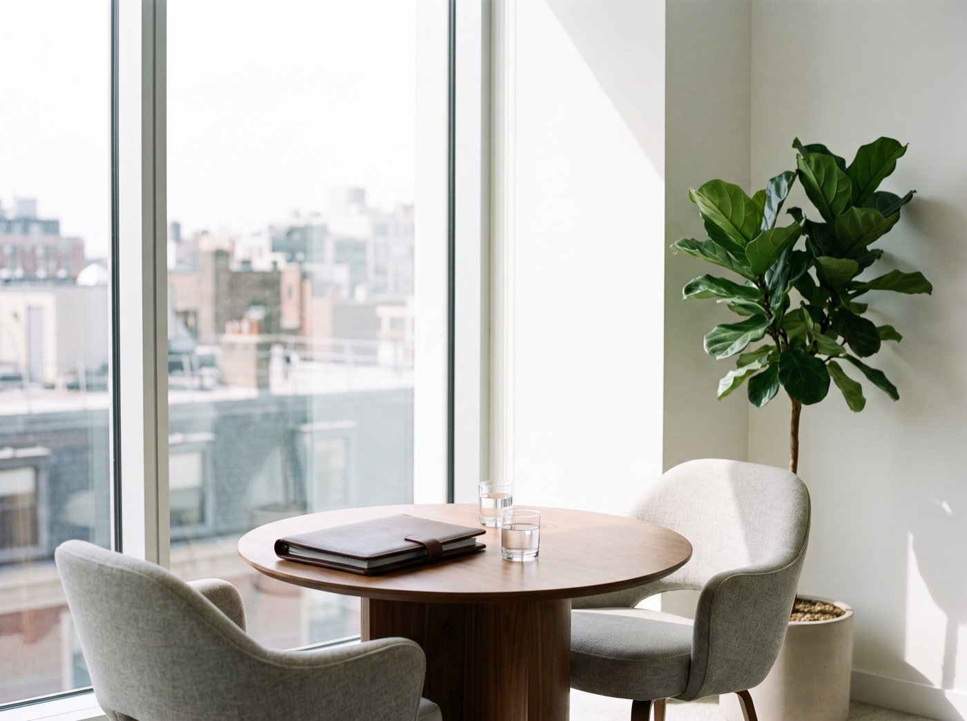 Round table with two chairs and a leather folder by a window