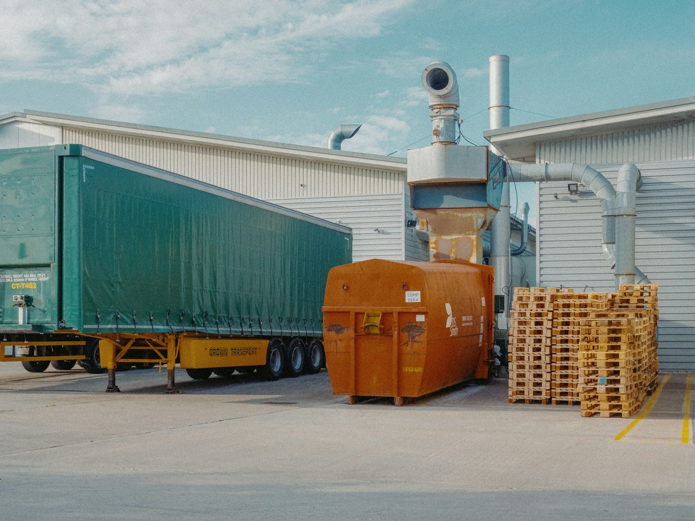 A freight trailer and stacked pallets in a warehouse yard