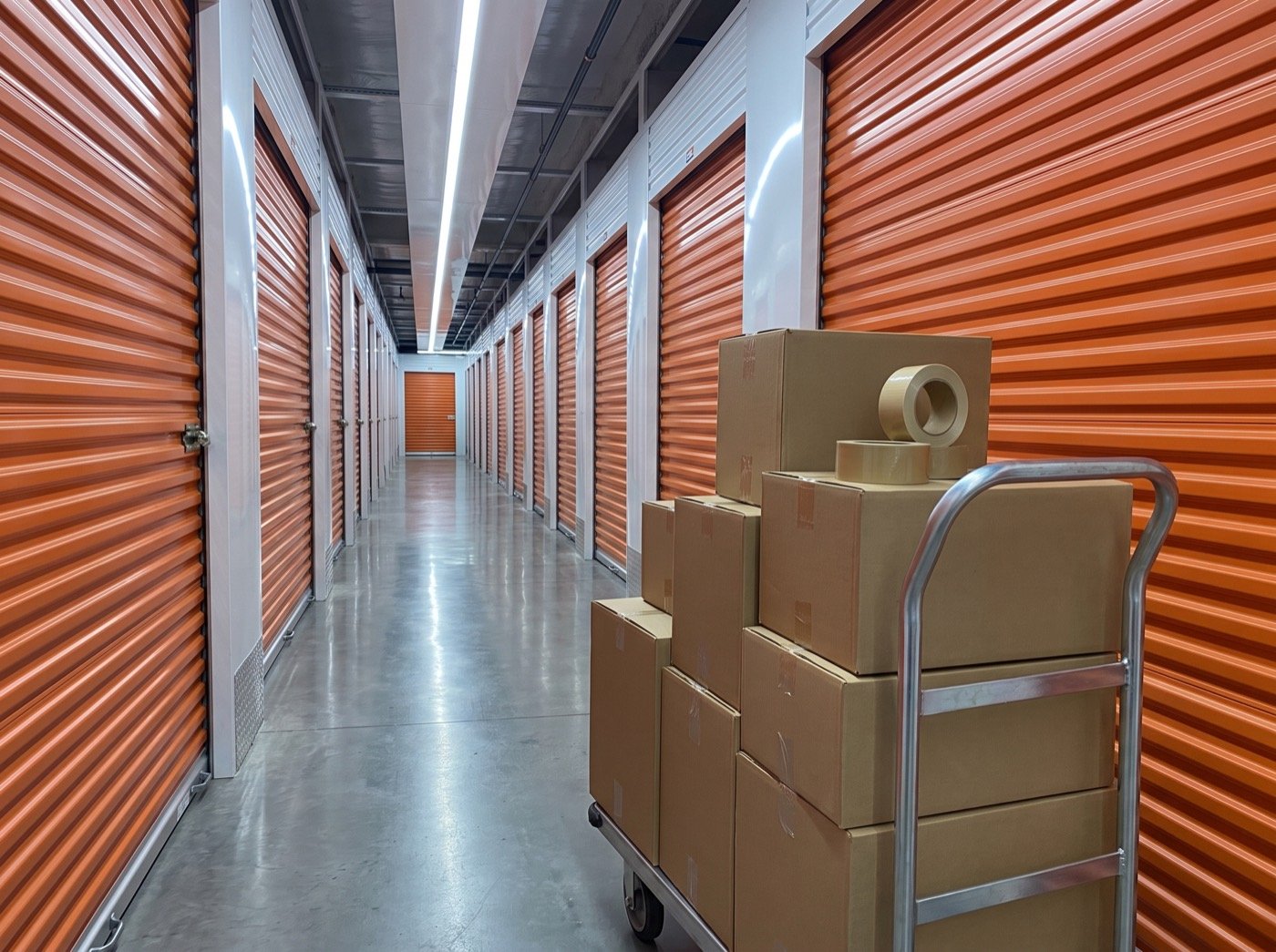 Hand truck with boxes in a corridor of orange storage doors