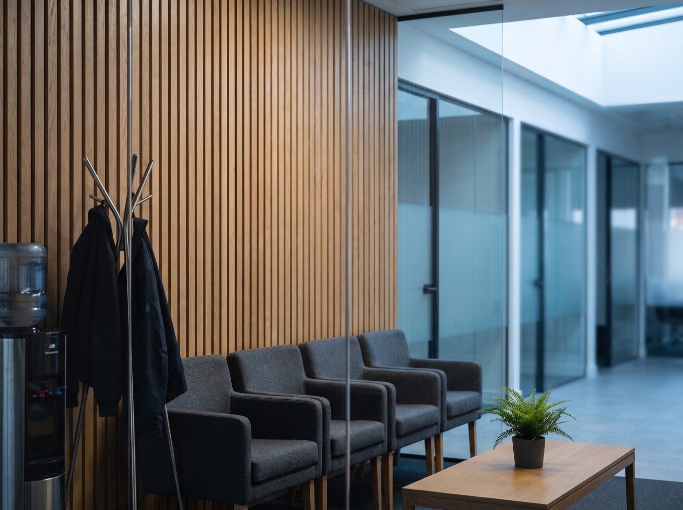 Row of chairs and glass-walled meeting rooms in a reception lounge