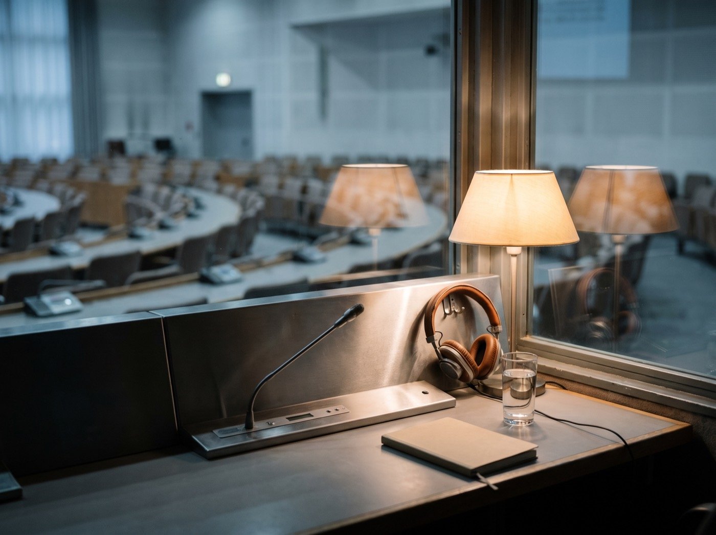 Headphones and microphone in an interpreter's booth overlooking a hall