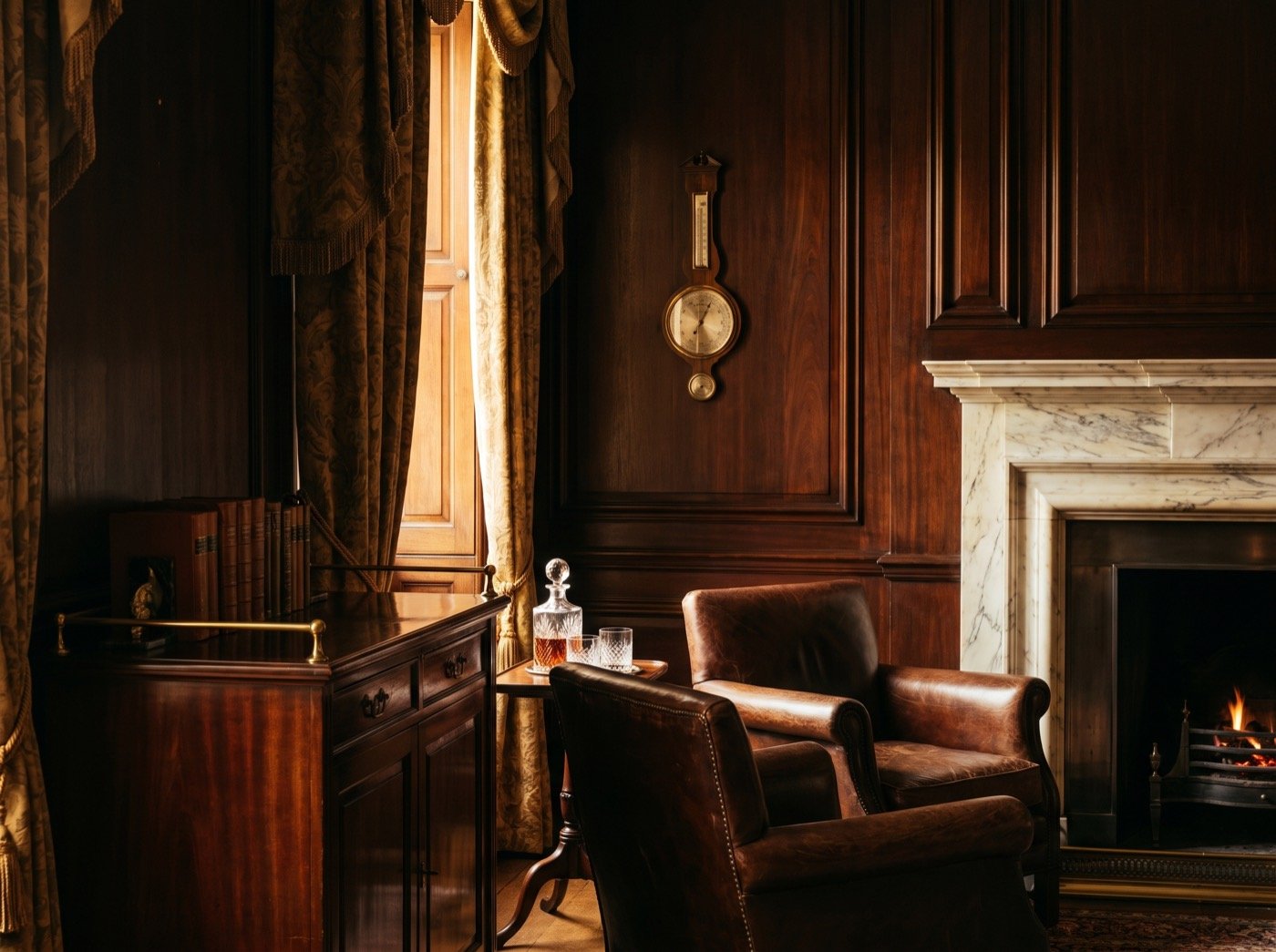 Leather armchairs and a decanter in a mahogany-panelled library